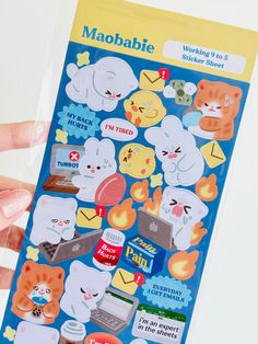 a person holding up a sticker sheet with cats and other things on it in their hands