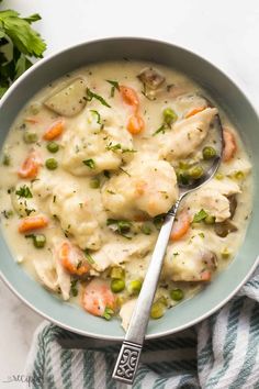 a bowl filled with chicken and dumpling soup on top of a striped towel next to a spoon