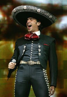 a man wearing a sombrero and singing into a microphone with his mouth wide open