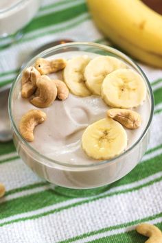 a glass bowl filled with bananas and cashews on top of a green table cloth