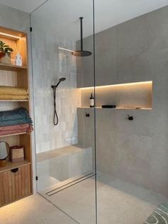 a walk in shower sitting next to a wooden shelf