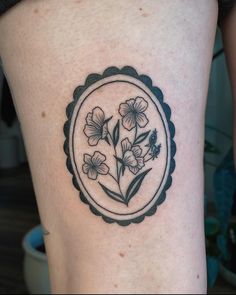 a woman's thigh with flowers in a circle tattoo on the side of her leg