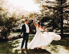 a bride and groom walking through the grass