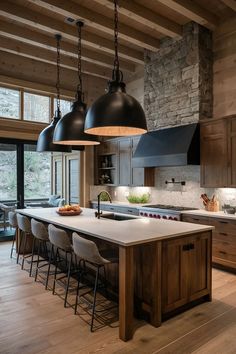 a kitchen with wooden floors and black pendant lights hanging from the ceiling over the island