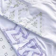 two white t - shirts with embroidered letters on them