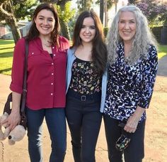 three women standing next to each other on a sidewalk