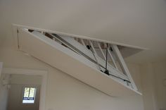 an attic loft with white walls and wooden stairs