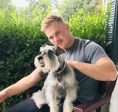 a man sitting in a chair with a dog on his lap looking at the camera