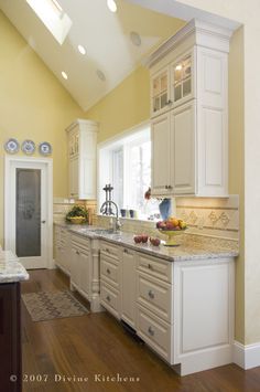 a large kitchen with white cabinets and wood floors