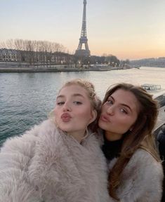 two women standing next to each other in front of the eiffel tower