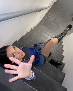 a woman is sitting on the stairs with her hand up