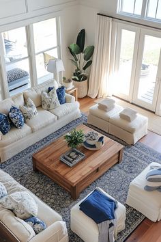 a living room filled with white couches and blue rug on top of a hard wood floor