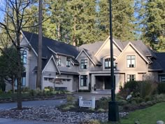 a large house with lots of windows and trees in the front yard, surrounded by rocks