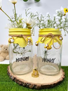 two mason jars with bees and flowers in them