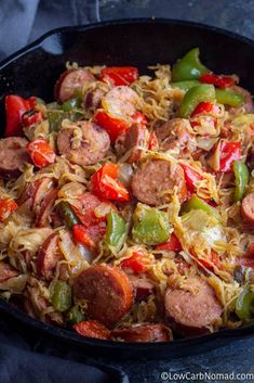 a skillet filled with sausage, peppers and noodles