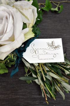 a bouquet of white roses sitting on top of a wooden table next to a name tag