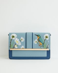 Key Features:



Nature-Inspired Design: Our Kingfisher Green rustic bag from the hero narrative Morning Song brings the essence of the English countryside to your outfit. The pastel blue hue evokes images of rambling meadows and dreamy riversides where our beautiful friend, the Kingfisher, thrives.


Functional Crossbody Strap: Designed with a crossbody strap, offering you the freedom to explore your surroundings on carefree jaunts.


Durable Construction: Crafted from 100% Polyurethane outer a Casual Blue Embroidered Shoulder Bag, Blue Rectangular Shoulder Bag With Floral Embroidery, Spring Floral Embroidered Crossbody Shoulder Bag, Embroidered Blue Crossbody Bag, Blue Cross Body Bag, Wedding Wine Gift, Morning Songs, Luxury Christmas Gifts, Blue Cross