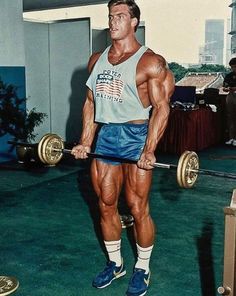 a man standing in the middle of a gym holding a barbell