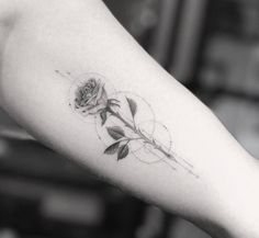 a black and white photo of a rose tattoo on the arm