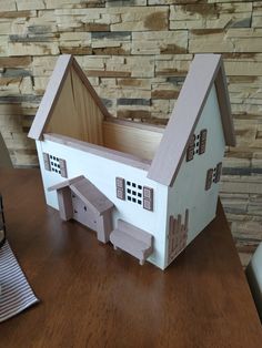 a doll house with furniture and accessories on a wooden table in front of a stone wall