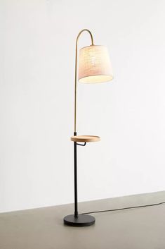 a floor lamp with a white shade on it's side and a black base