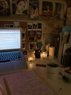 an open laptop computer sitting on top of a desk next to a cup and candles