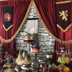 a table topped with lots of food next to red drapes covered in tassels