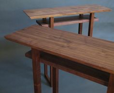 two wooden tables sitting next to each other on top of a gray surface with no one around them