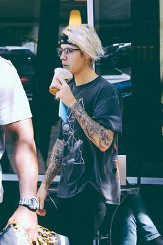 a young man with tattoos eating an ice cream cone