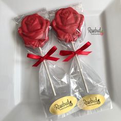 two lollipops wrapped in cellophane and tied with red ribbon on a white plate