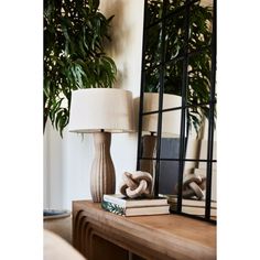 a lamp sitting on top of a wooden table next to a mirror and bookend