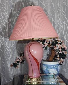 a pink lamp sitting on top of a table next to a vase with flowers in it