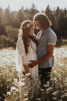 a pregnant couple standing in the middle of a field