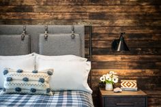 a bed with two nightstands next to it and a wooden wall behind the headboard