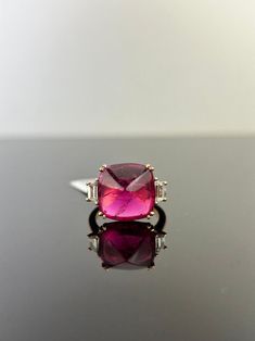 A stunning three stone engagement ring, with a 9.13 carat transparent natural Pink Tourmaline centre stone and 0.50 carat trapeze side stone VS2 quality Diamonds. The Tourmaline is of great lustre and has an ideal pink color. All set in 18K rose gold, with yellow gold prongs. Currently a ring size US 7, but can be resized. Certificate available. 18K Pink Gold : 6.14 Gms Rubilite : 9.13 Ctw Diamond : 0.50 Ctw Luxury Tourmaline Gemstones For Wedding, Elegant Three Stone Tourmaline Jewelry, Luxury Tourmaline Wedding Gemstones, Elegant Faceted Tourmaline Ring, Elegant Baguette Cut Tourmaline Jewelry, Luxury Tourmaline Gemstones With Accent Stones, Elegant Baguette-cut Tourmaline Jewelry, Luxury Pink Tourmaline Jewelry, Pink Round Cut Tourmaline Jewelry