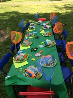 a table set up for a birthday party with plastic chairs, plates and cups on it