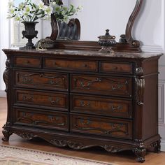 an ornate dresser with mirror and flowers on top