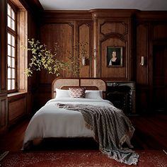 a bedroom with wood paneled walls and a bed in the middle, along with a rug on the floor