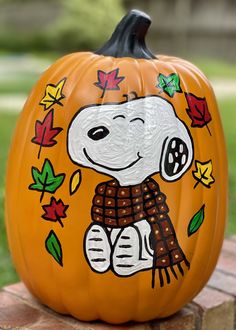 a painted pumpkin with a cartoon dog on it's face and leaves surrounding it