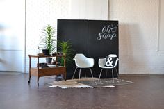 two white chairs sitting in front of a blackboard