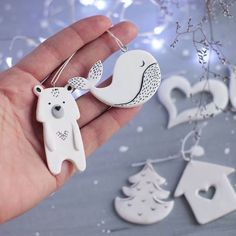 a hand holding a white bear and bird ornament in it's palm