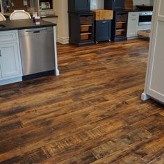 a kitchen with wood flooring and white cabinets in the background is a stainless steel dishwasher