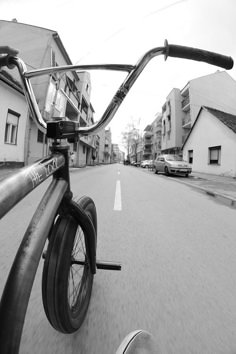 a bicycle is parked on the street in front of some buildings and cars driving down it