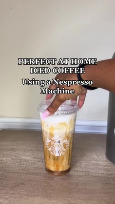 someone holding a cup with liquid in it and the words perfect at home iced coffee using a nespess machine