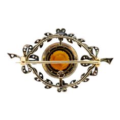 This exquisite Edwardian brooch is a true work of art that will catch the eye of anyone who sets their sights on it. The brooch features a stunning bow and foliate motif, with a central piece that boasts a brilliant cut round citrine, surrounded by a circle of rose cut diamonds. The brooch is further adorned with rose cut and old cut diamonds, arranged in a beautiful bow foliate motif. The mount is made of silver topped yellow gold, which adds an extra touch of elegance and sophistication. On th Luxury Round Brooches For Collectors, Luxury Round Collectible Brooches, Luxury Round Cabochon Brooch, Luxury Cabochon Brooch, Luxury Round Cabochon Brooches, Victorian Yellow Gold Brooches With Gemstone, Elegant Round Brooch With Intricate Design, Elegant Round Brooches With Intricate Design, Antique Jeweled Brooches For Formal Occasions