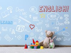 two stuffed animals sitting next to each other in front of a wall with writing on it