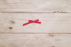 a red bow with white polka dots on it sitting on a wooden table next to a pair of scissors