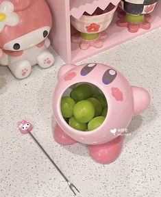 a bowl filled with green apples sitting on top of a counter next to hello kitty figurines