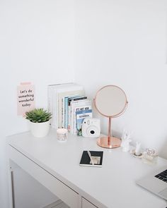 a white desk with a laptop and books on it, along with a potted plant