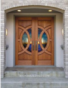 two wooden doors with stained glass in front of a brick wall and steps leading up to them